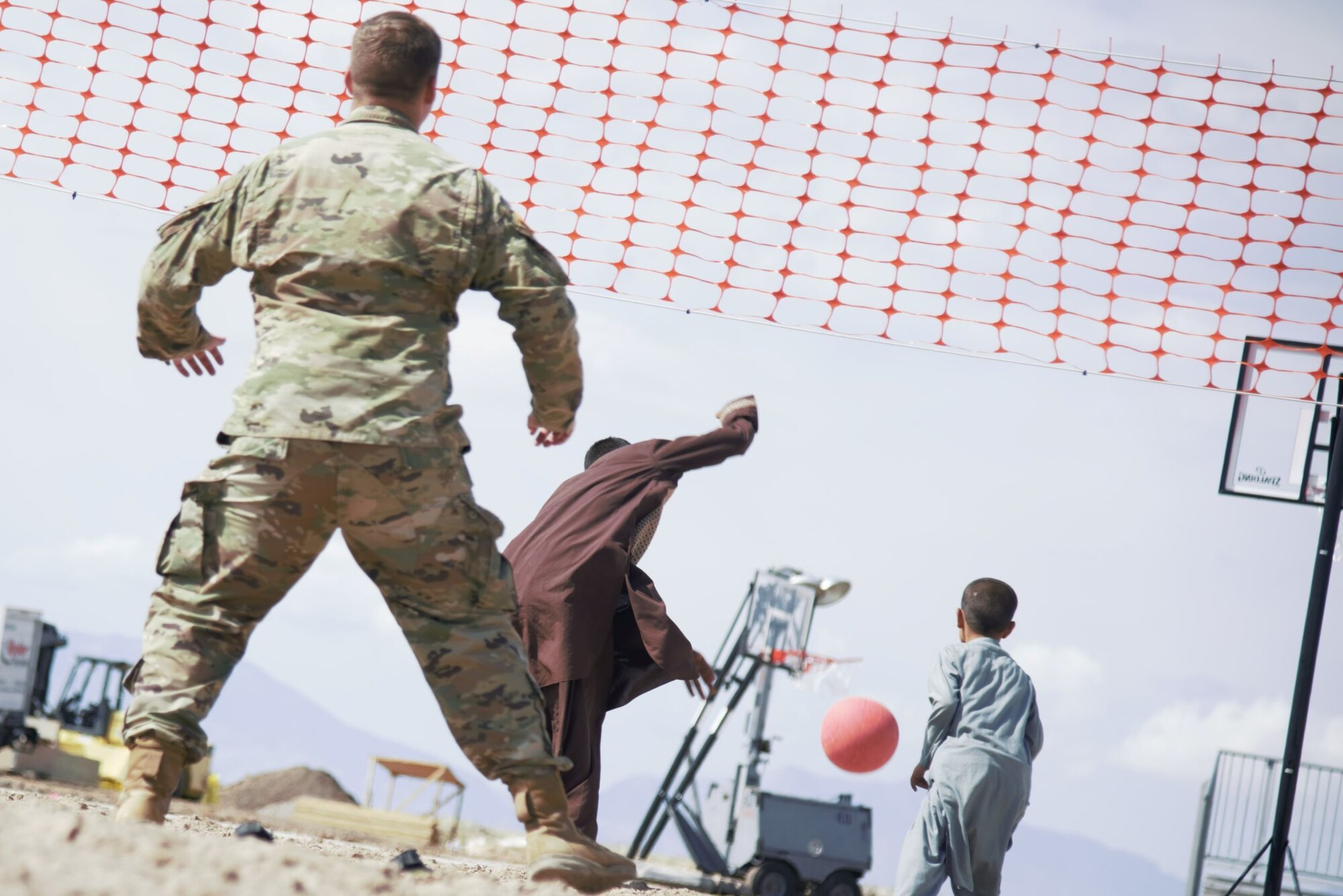 Afghan children joyously chase the ball after a Soldier assigned to Task Force-Holloman returns the ball during an impromptu volleyball game at U.S. Holloman Air Force Base, New Mexico, Oct. 1, 2021. The Department of Defense, through U.S. Northern Command, and in support of the Department of State and Department of Homeland Security, is providing transportation, temporary housing, medical screening, and general support for at least 50,000 Afghan evacuees at suitable facilities, in permanent or temporary structures, as quickly as possible. This initiative provides Afghan evacuees essential support at secure locations outside Afghanistan. (U.S. Navy photo by Mass Communications Specialist 1st Class Sarah Rolin)