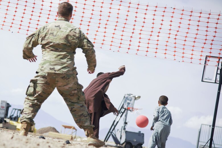 Afghan children joyously chase the ball after a Soldier assigned to Task Force-Holloman returns the ball during an impromptu volleyball game at U.S. Holloman Air Force Base, New Mexico, Oct. 1, 2021. The Department of Defense, through U.S. Northern Command, and in support of the Department of State and Department of Homeland Security, is providing transportation, temporary housing, medical screening, and general support for at least 50,000 Afghan evacuees at suitable facilities, in permanent or temporary structures, as quickly as possible. This initiative provides Afghan evacuees essential support at secure locations outside Afghanistan. (U.S. Navy photo by Mass Communications Specialist 1st Class Sarah Rolin)