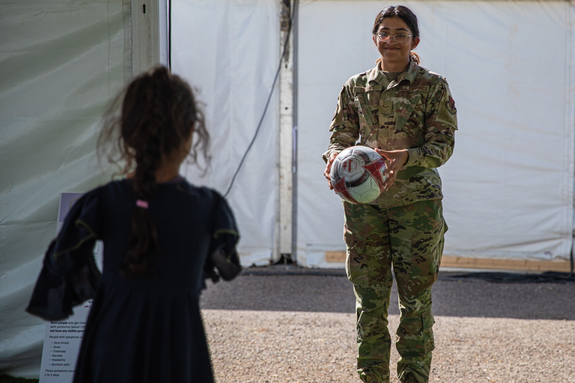 An Airman attached to Task Force-Holloman plays catch with an Afghan child at Aman Omid Village on Holloman Air Force Base, New Mexico, Oct. 7, 2021. The Department of Defense, through U.S. Northern Command, and in support of the Department of Homeland Security, is providing transportation, temporary housing, medical screening, and general support for at least 50,000 Afghan evacuees at suitable facilities, in permanent or temporary structures, as quickly as possible. This initiative provides Afghan personnel essential support at secure locations outside Afghanistan. (U.S. Army photo by Pfc. Anthony Sanchez)