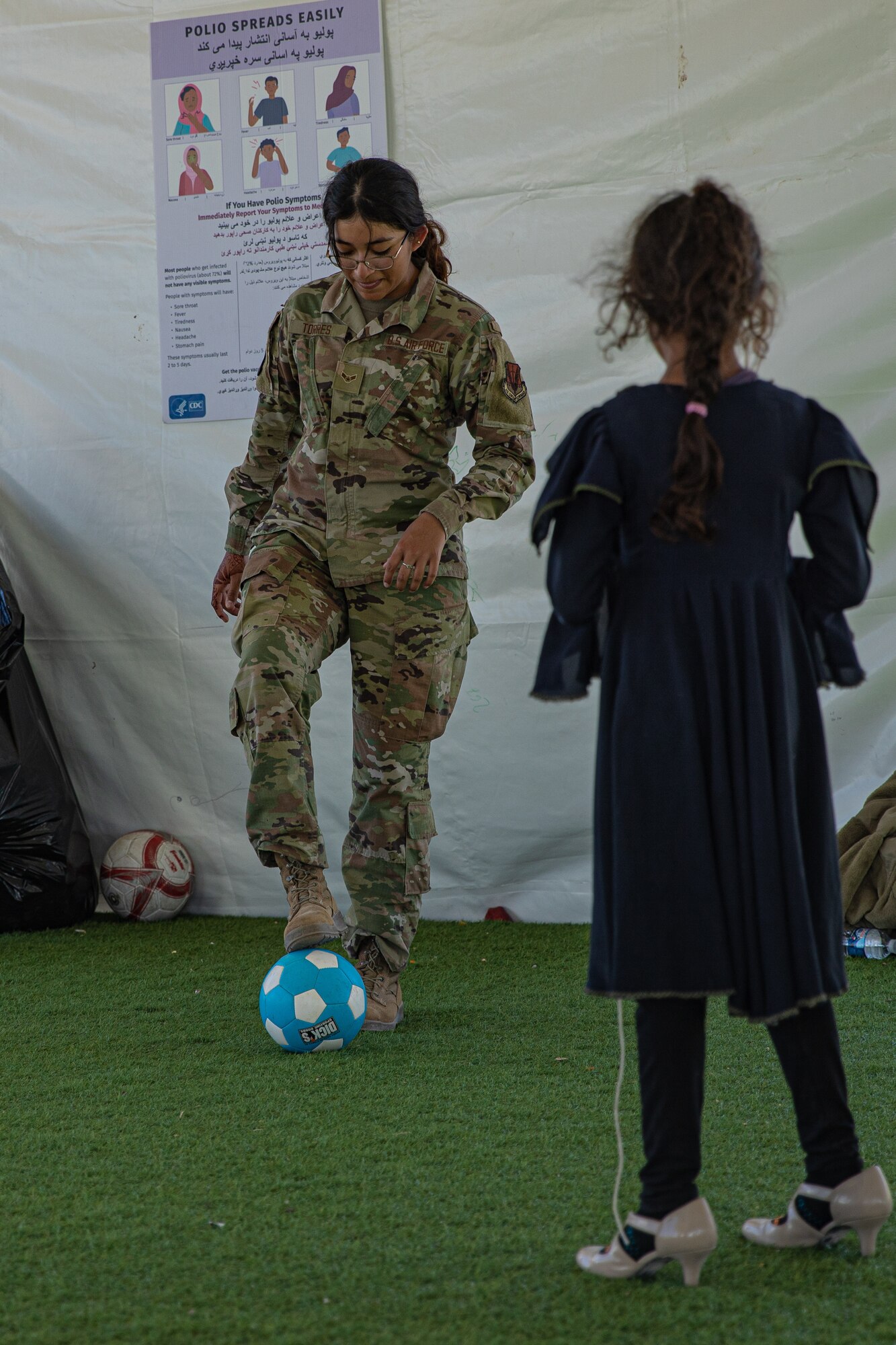 An Airman attached to Task Force-Holloman plays soccer with an Afghan child at Aman Omid Village on Holloman Air Force Base, New Mexico, Oct. 7, 2021. The Department of Defense, through U.S. Northern Command, and in support of the Department of Homeland Security, is providing transportation, temporary housing, medical screening, and general support for at least 50,000 Afghan evacuees at suitable facilities, in permanent or temporary structures, as quickly as possible. This initiative provides Afghan personnel essential support at secure locations outside Afghanistan. (U.S. Army photo by Pfc. Anthony Sanchez)