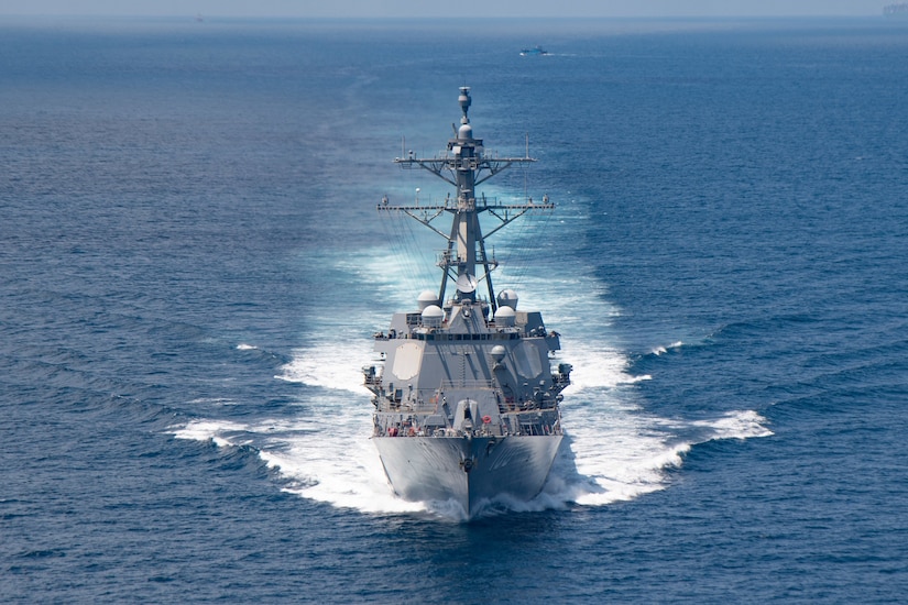A navy ship moves through the water.