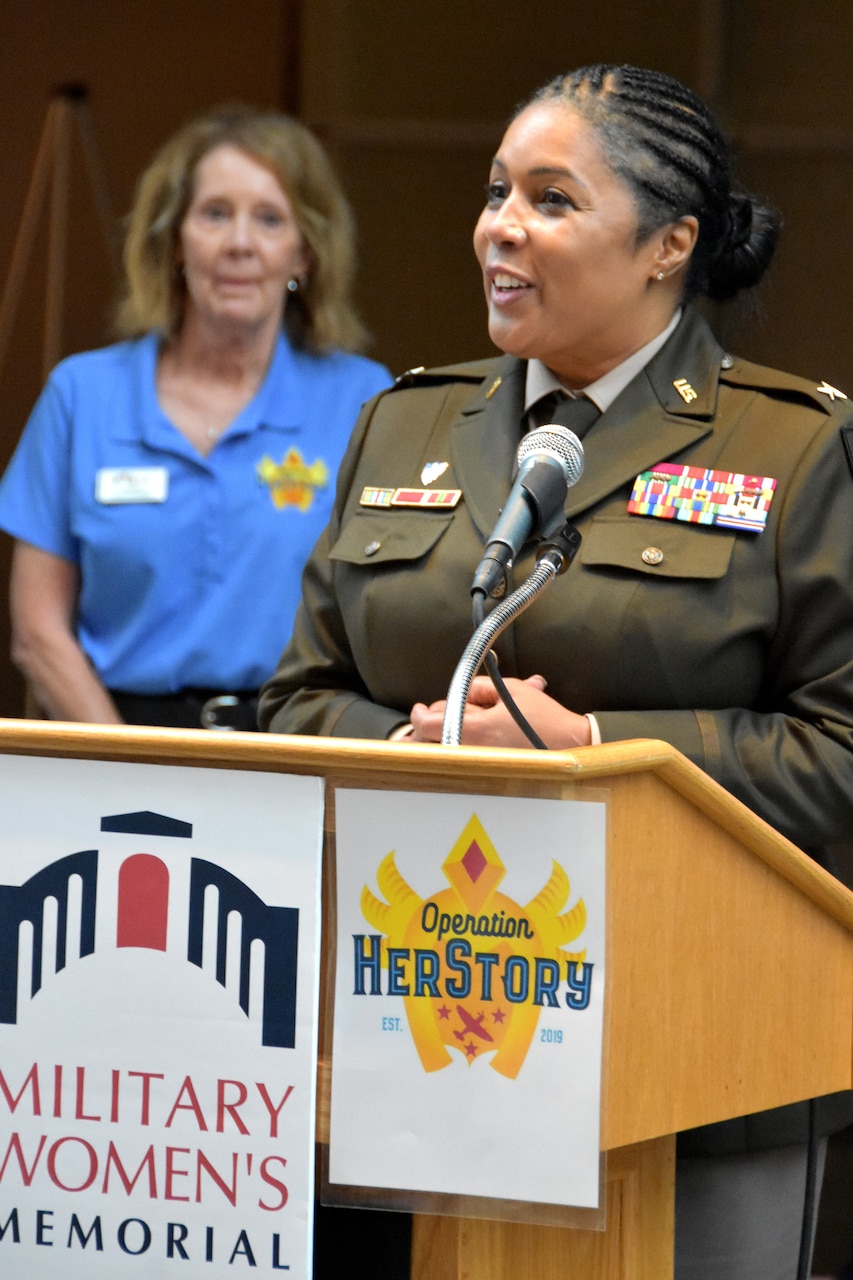 A woman in a military uniform stands at a podium.