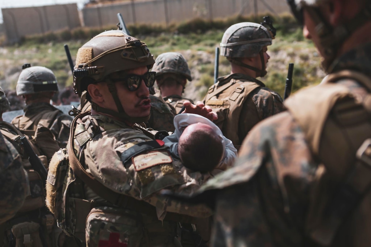 An Airman comforts an infant during an evacuation at Hamid Karzai International Airport, Kabul, Afghanistan, Aug. 20, 2021. U.S. service members and coalition partners assisted the Department of State with a non-combatant evacuation operation in Afghanistan as a part of Operation Allies Refuge. (U.S. Marine Corps photo by Sgt. Isaiah Campbell)