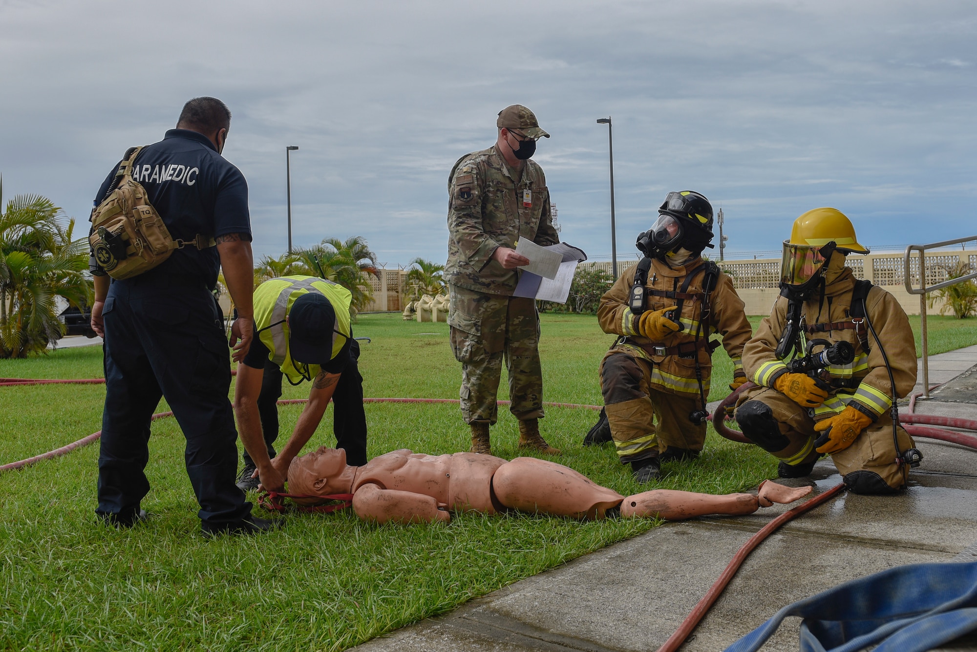 Firefighters and paramedics surrounding a mannequin during an exercsie.