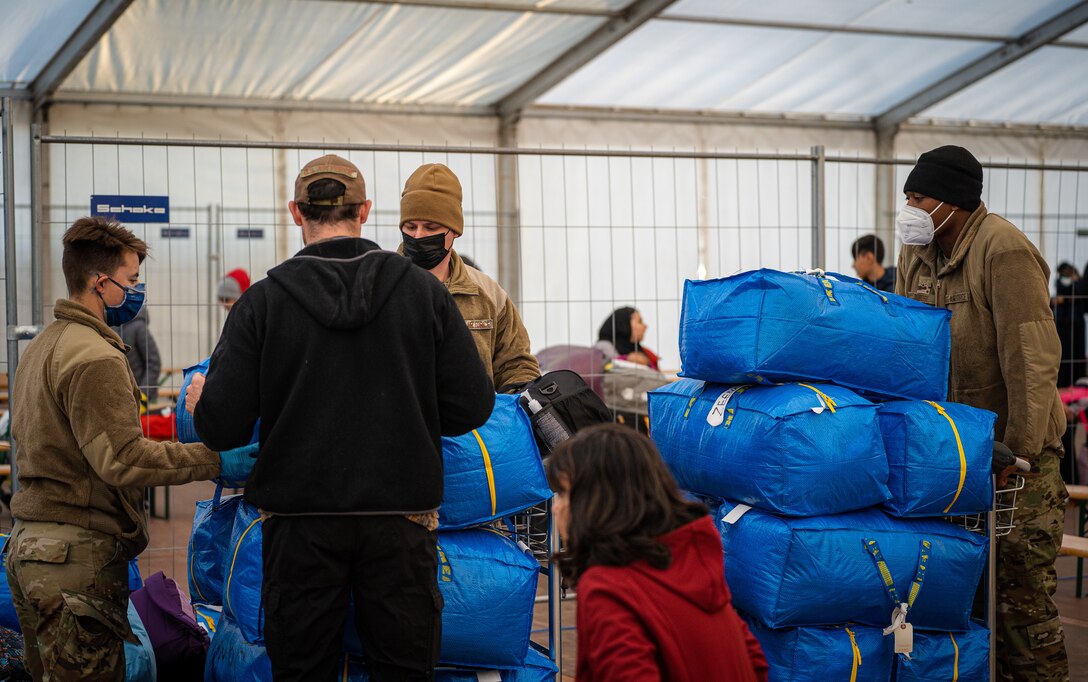 Evacuees and Airmen load luggage onto carts.
