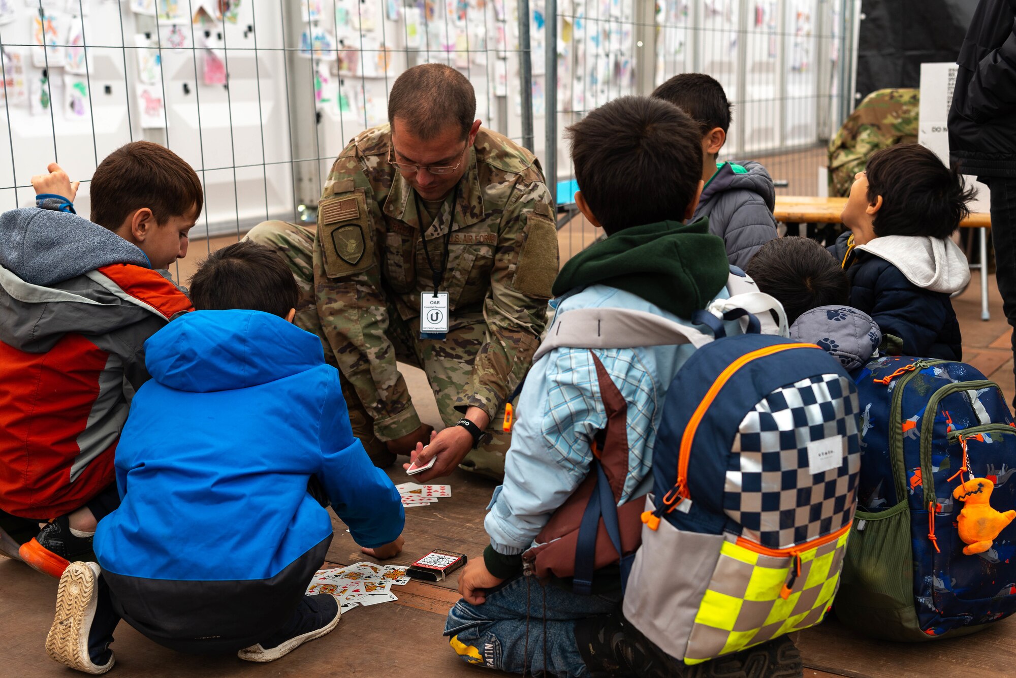 Airman plays cards with evacuees.