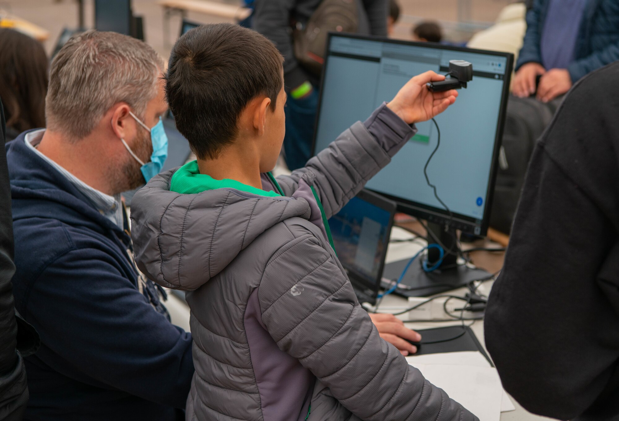 Evacuees helps TSA agent take photos at checkpoint.