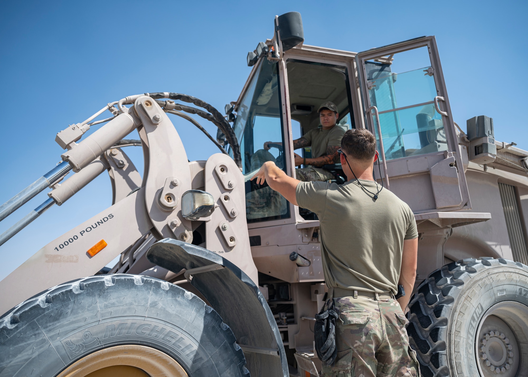 Tech. Sgt. Sean Ofiara directs U.S. Air Force Staff Sgt. Robert Ignacio, assigned to the 443rd Air Expeditionary Squadron, while preparing to move cargo at Al Asad Air Base, Iraq, Sept. 22, 2021.