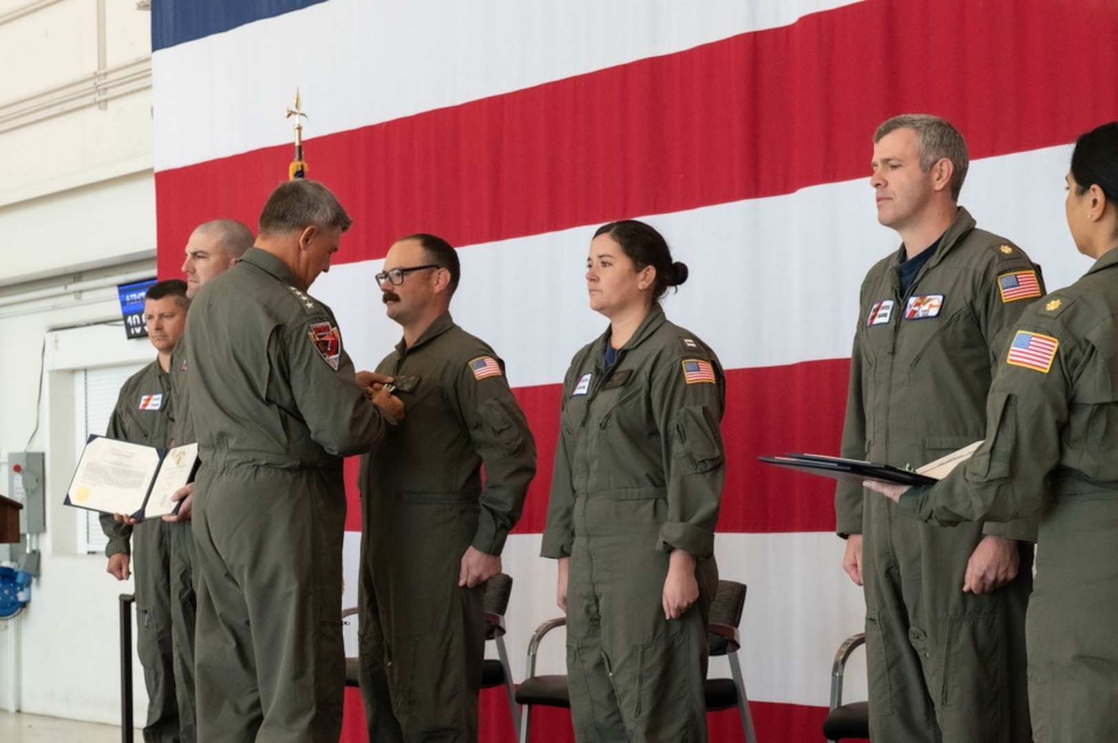 Adm. Karl Schultz, commandant of the Coast Guard, presents the Coast Guard Commendation Medal to members at Air Station Cape Cod, Oct.10, 2021. The Commendation Medal is awarded to members for their meritorious service that has resulted in unusual and outstanding achievement. (U.S. Coast Guard photo by Petty Officer 3rd Class Emma Fliszar/Released)