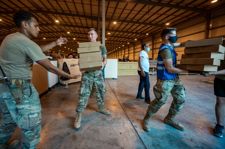 Airmen work together to unload food for Afghanistan evacuees, Aug. 23, 2021, at Al Udeid Air Base, Qatar.