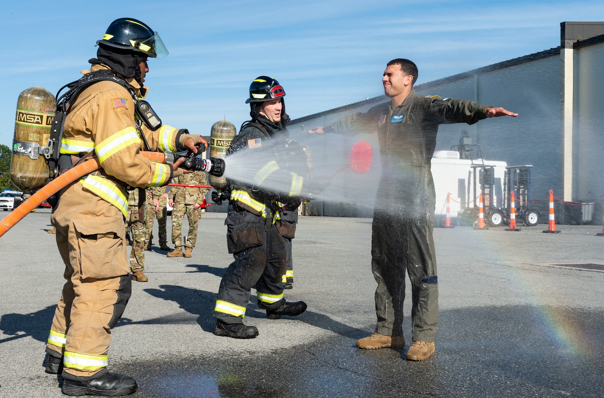 Firemen from the 436th Civil Engineer Squadron fire department, simulate decontaminating Senior Airman Gianni Maldonado, 9th Airlift Squadron loadmaster, during a Force Protection Major Accident Response Exercise at Dover Air Force Base, Delaware, Oct. 7, 2021. The three-day exercise tested the response capabilities of Team Dover through various scenarios in an effort to strengthen their ability to provide rapid-global mobility in challenging conditions.(U.S. Air Force photo by Roland Balik)