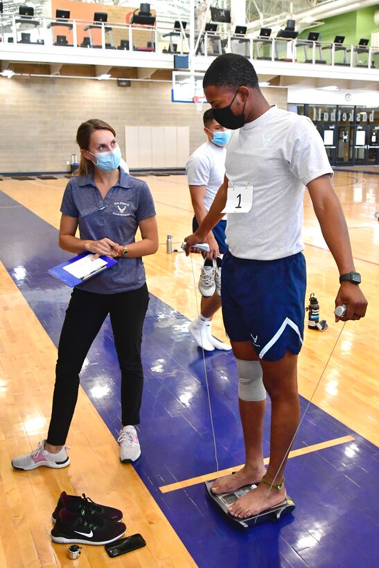 An Airman takes strength measurement test while an observer watches.