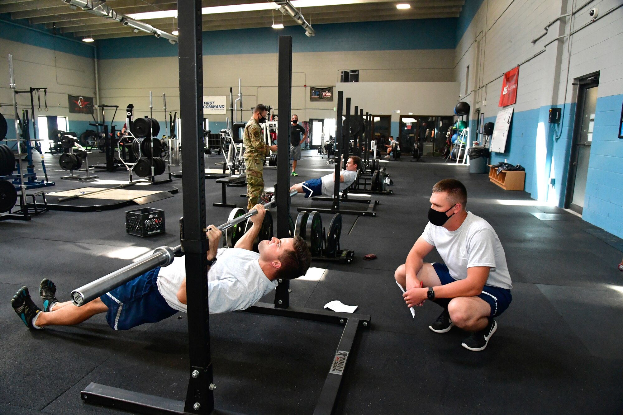 An Airman performs modified pull-ups while another Airman watches.