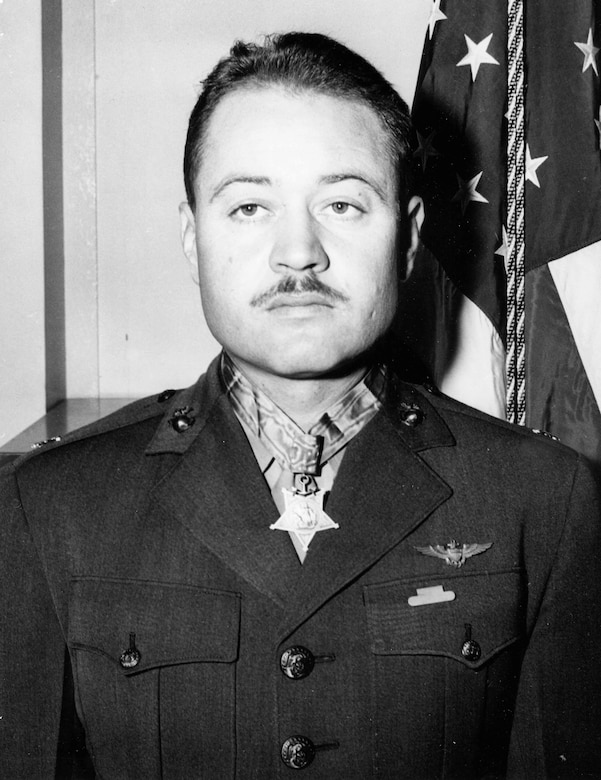 A man standing in front of a U.S. flag wears the Medal of Honor around his neck.