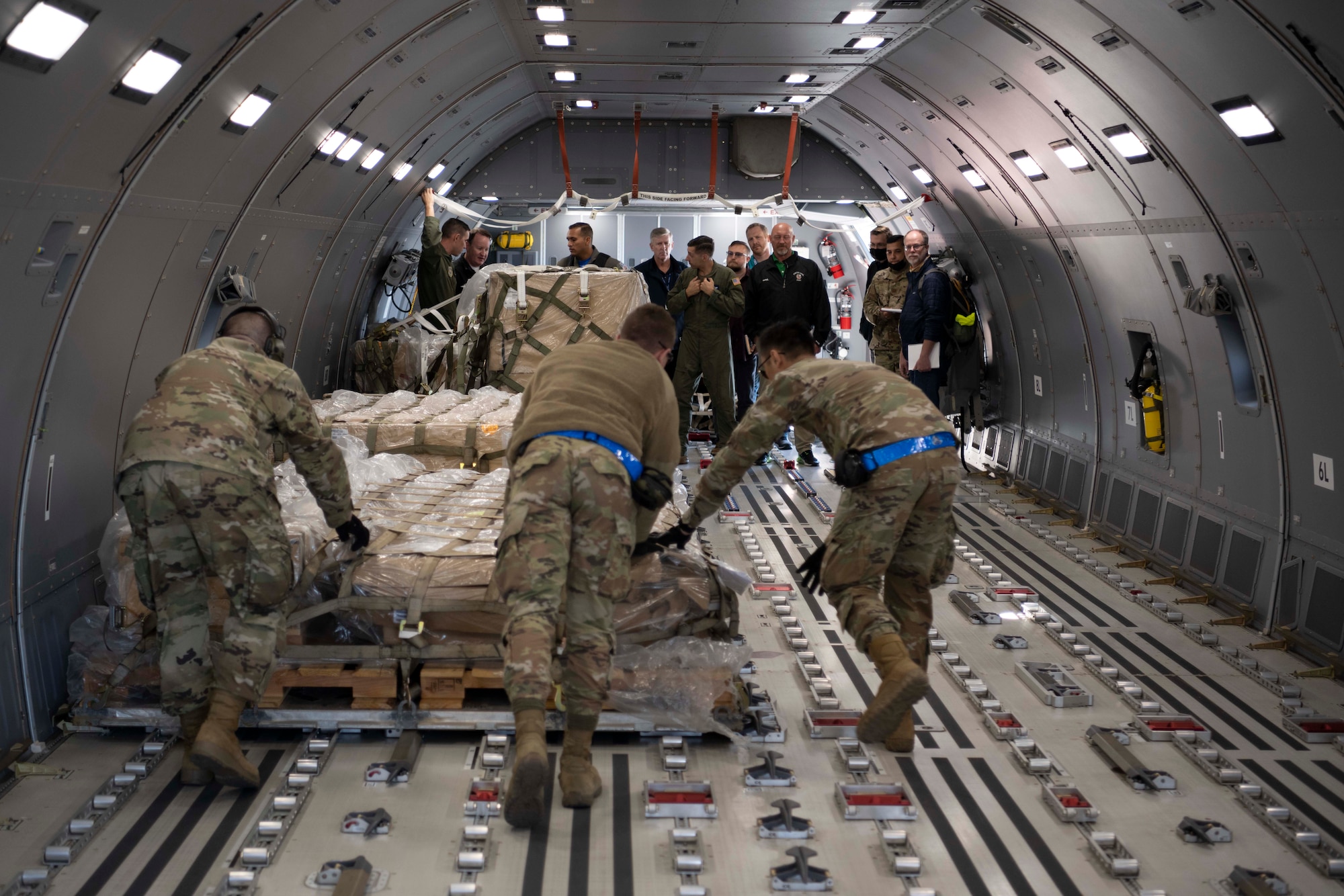people spectate Airmen push cargo in an aircraft