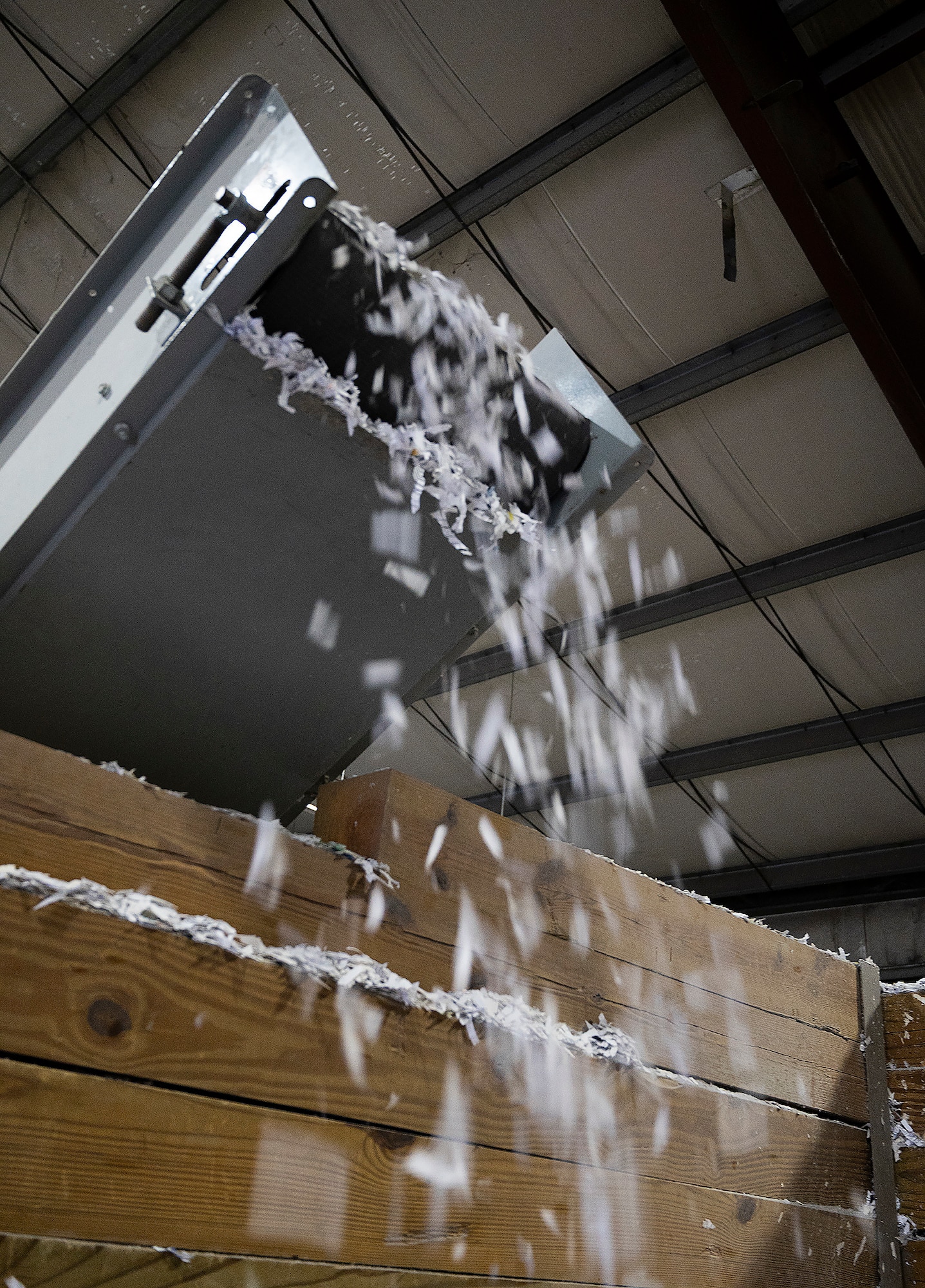 Shreds of paper flutter off a conveyer belt Sept. 22, 2021, inside the Recycling Center at Wright-Patterson Air Force Base, Ohio. Center personnel shred documents containing official information  or personal data gathered from base commands prior to baling and selling the product. (U.S. Air Force photo by R.J. Oriez)