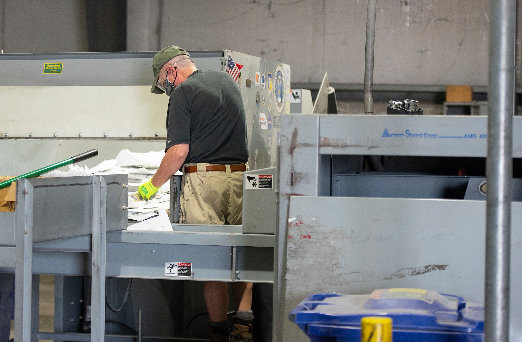 Bob Parsons, 88th Force Support Squadron, sorts through office paper and feeds it into a shredder Sept. 22, 2021, inside the Recycling Center at Wright-Patterson Air Force Base, Ohio. Center personnel shred documents containing official information or personal data gathered from base commands prior to baling and selling the product. (U.S. Air Force photo by R.J. Oriez)