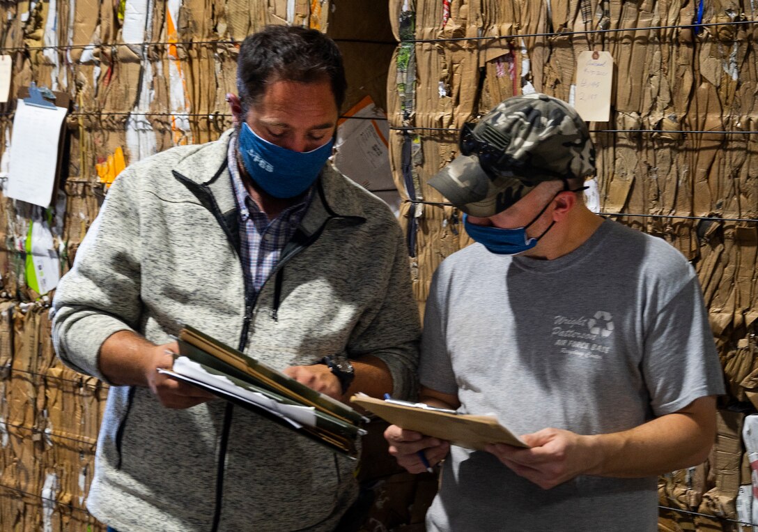 Thomas Doucette (left), 88th Force Support Squadron Recycling Center manager, and Dave Matheney compare notes during the loading of cardboard bales on a buyer’s truck Sept. 27, 2021, at Wright-Patterson Air Force Base, Ohio. Each bale of cardboard behind them weighs more than a ton. (U.S. Air Force photo by R.J. Oriez)