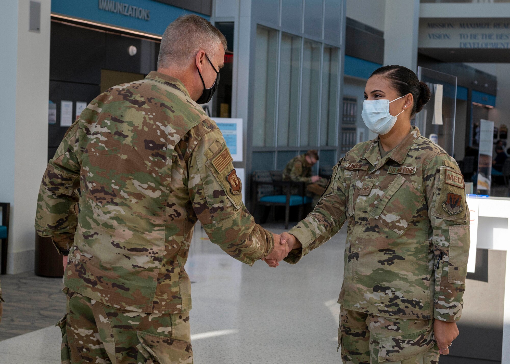 U.S. Air Force Maj. Gen. Michael G. Koscheski, left, Fifteenth Air Force commander, coins Senior Airman Alicia Zamora, immunization technician, at Seymour Johnson Air Force Base, North Carolina, Sept. 28, 2021.