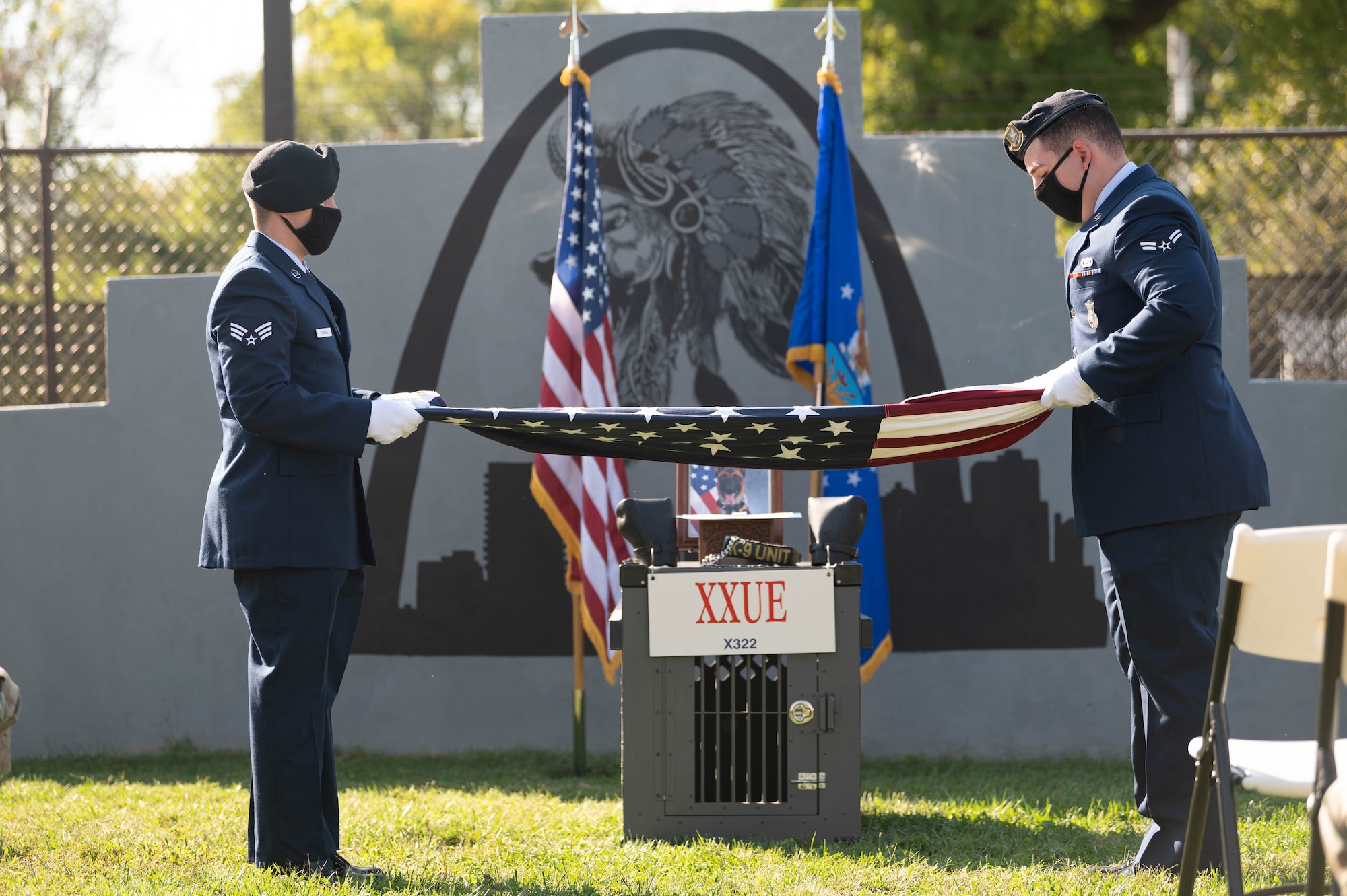 Honor Guard members fold a U.S. flag at a military working dog memorial.