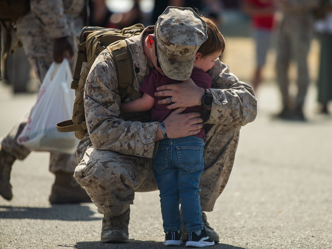 U.S. Marine Corps Staff Sgt. Payden Varwig, with 2nd Battalion, 1st Marine Regiment, 1st Marine Division (2/1) embraces his son during a 2/1 homecoming event at Camp Horno, Marine Corps Base Camp Pendleton, California on Oct. 3, 2021. The Marines with 2/1, known as the Professionals, were deployed in support of Special Purpose Marine Air-Ground Task Force - Crisis Response - Central Command for six months. (U.S. Marine Corps Photo by Lance Cpl. Cedar Barnes.)