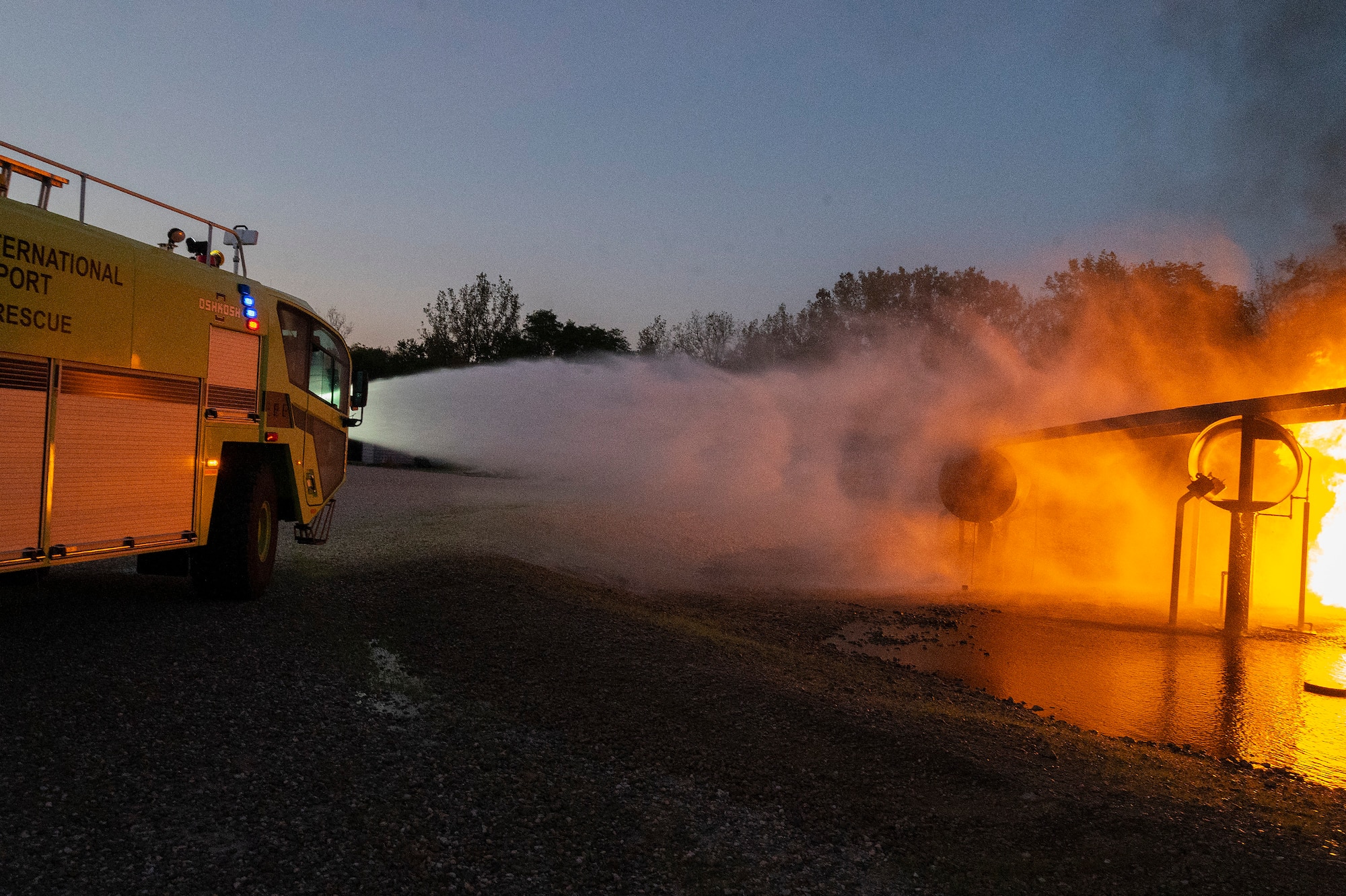The Dayton International Airport Fire Department crash truck sprays down a live training fire Oct. 5, 2021, at Wright-Patterson Air Force Base, Ohio. The 788th Civil Engineer Squadron Fire Department hosts outside agencies, including fire departments from the Springfield, Columbus and Dayton airports, to give them the opportunity to work on aircraft-fire skills. (U.S. Air Force photo by R.J. Oriez)