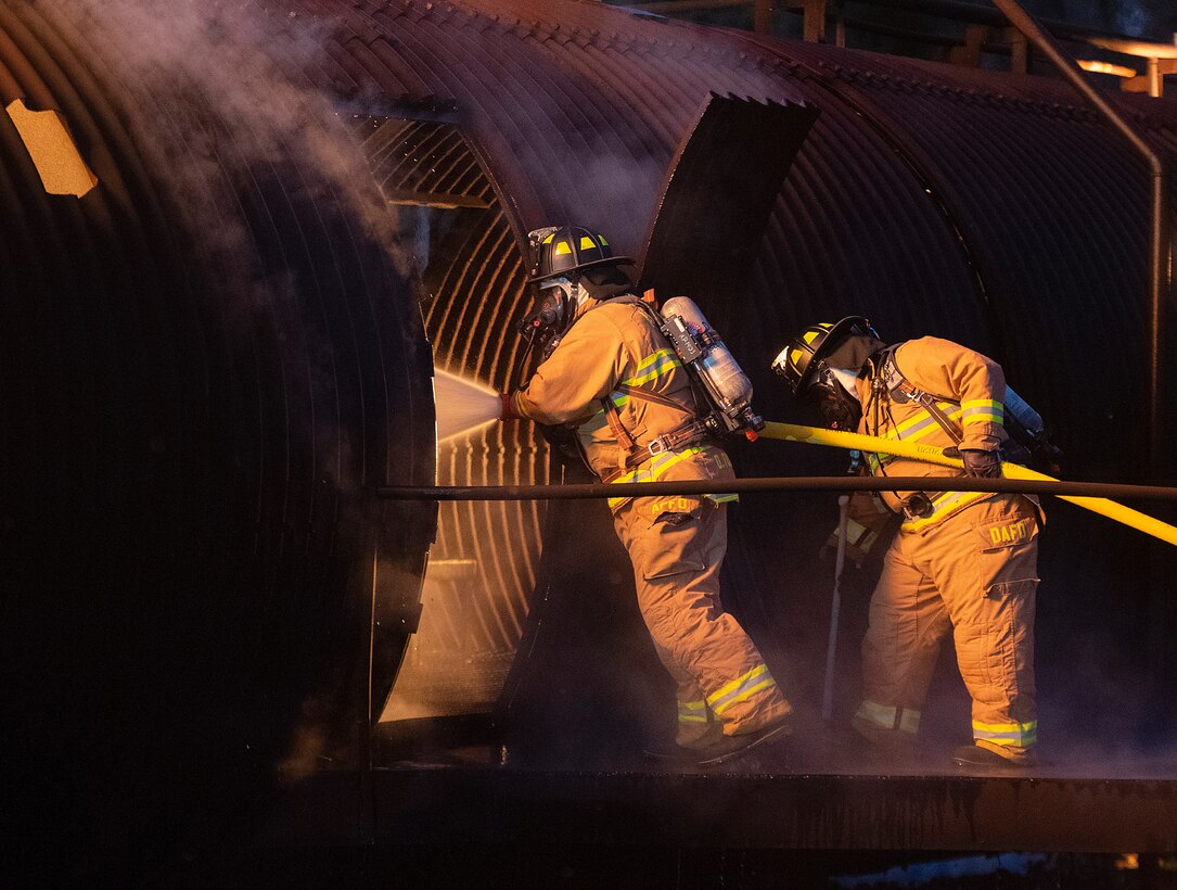 Dayton International Airport firefighters gain access to an aircraft fuselage mock-up with a training fire inside Oct. 5, 2021, at Wright-Patterson Air Force Base, Ohio. The training included knocking down the fire and conducting rescue procedures. (U.S. Air Force photo by R.J. Oriez)