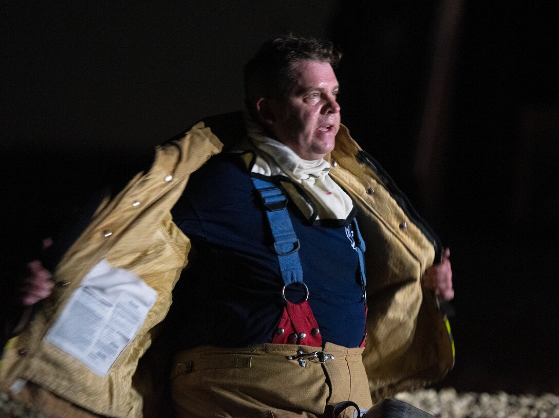 A sweaty Dayton International Airport firefighter strips off his bunker gear Oct. 5, 2021, at the end of nighttime training on Wright-Patterson Air Force Base, Ohio. Local firefighters had to deal with multiple fires through the evening as the Wright-Patt crew threw different scenarios at them. (U.S. Air Force photo by R.J. Oriez)