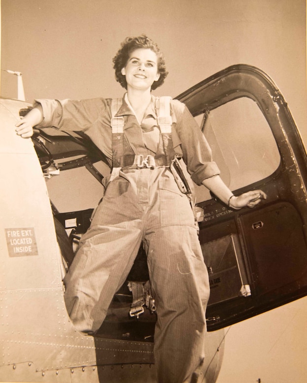 A World War II-era photo shows a woman in a flight suit stepping out of a military aircraft.