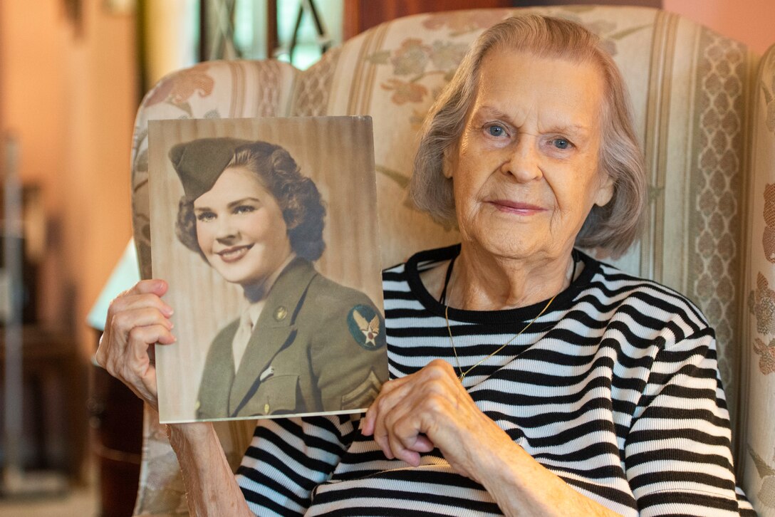 A woman holds an old photo of a woman in military uniform.