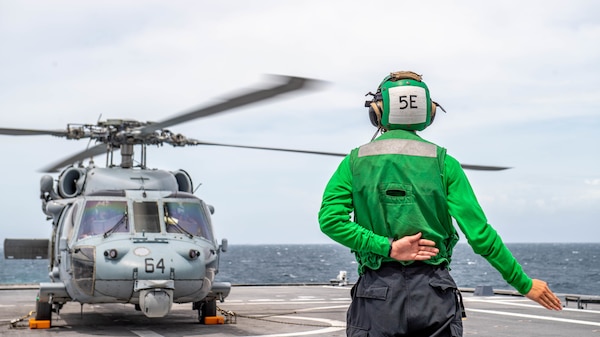 A Sailor signals to a MH-60S Sea Hawk Helicopter aboard the Independence-variant littoral combat ship USS Charleston (LCS 18), during flight operations.
