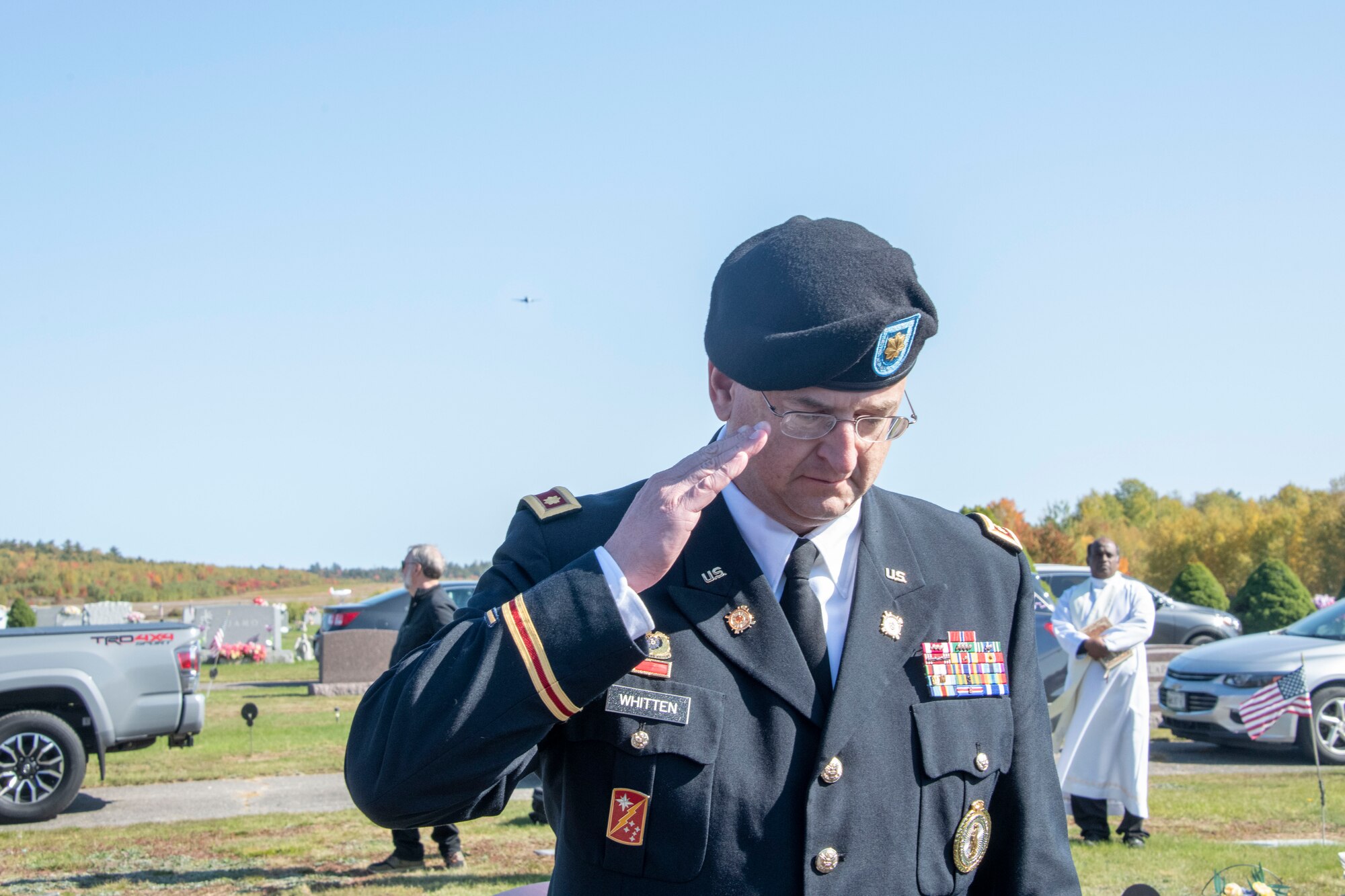 U.S. Army Maj. Jeff Whitten, Maine Army National Guard state partnership program director, salutes the flag after presenting it to the family of U.S. Army Air Forces 2nd Lt. Ernest Vienneau, former 97th Bombardment Group pilot, as a KC-46 Pegasus from the 97th Air Mobility Wing approaches in the distance at Millinocket, Maine, Oct. 9, 2021. After the folding, presenting, passing, lowering, or raising of the American Flag, U.S. military members salute the flag as a form of honor and respect. (U.S. Air Force photo by Staff Sgt. Cody Dowell)