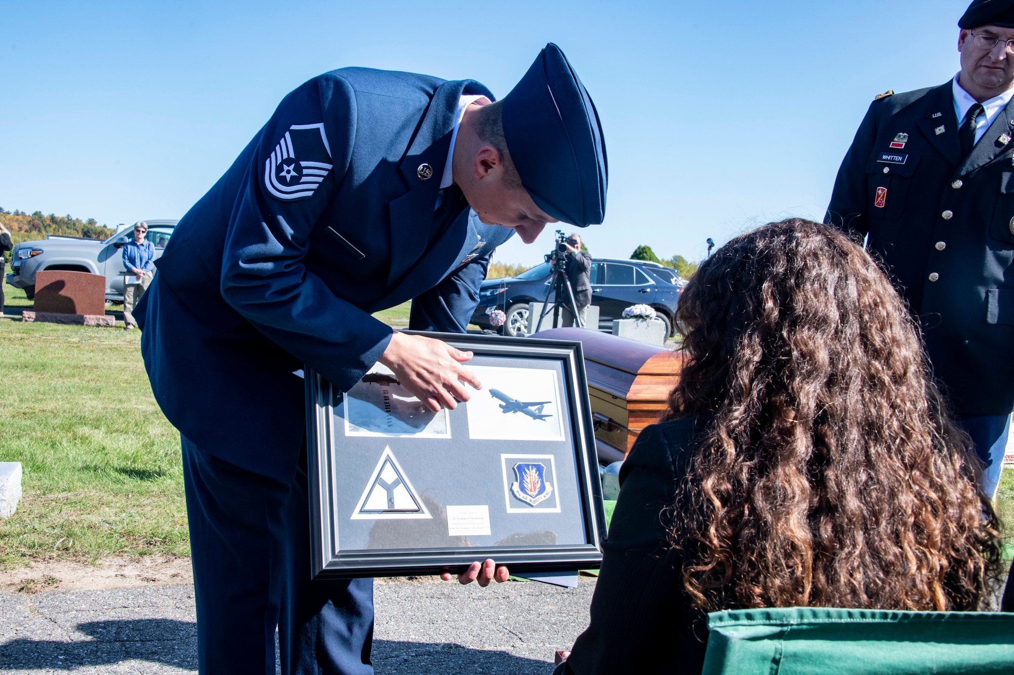 U.S. Air Force Master Sgt. Brad Edwards, 58th Airlift Squadron loadmaster, presents a plaque from the 97th Air Mobility Wing (AMW) to the family of U.S. Army Air Forces 2nd Lt. Ernest Vienneau, former 97th Bombardment Group pilot, during Vienneau’s funeral at Millinocket, Maine, Oct. 9, 2021. The plaque showcased the aircraft that Vienneau flew and the aircraft that was flown over the funeral by members of the 97th AMW. (U.S. Air Force photo by Staff Sgt. Cody Dowell)