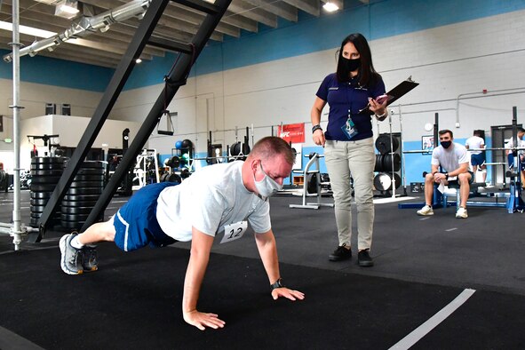 An Airman performs push-ups while an observer watches.