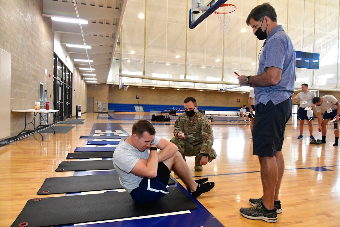 An Airman performs sit-ups while an observer watches.