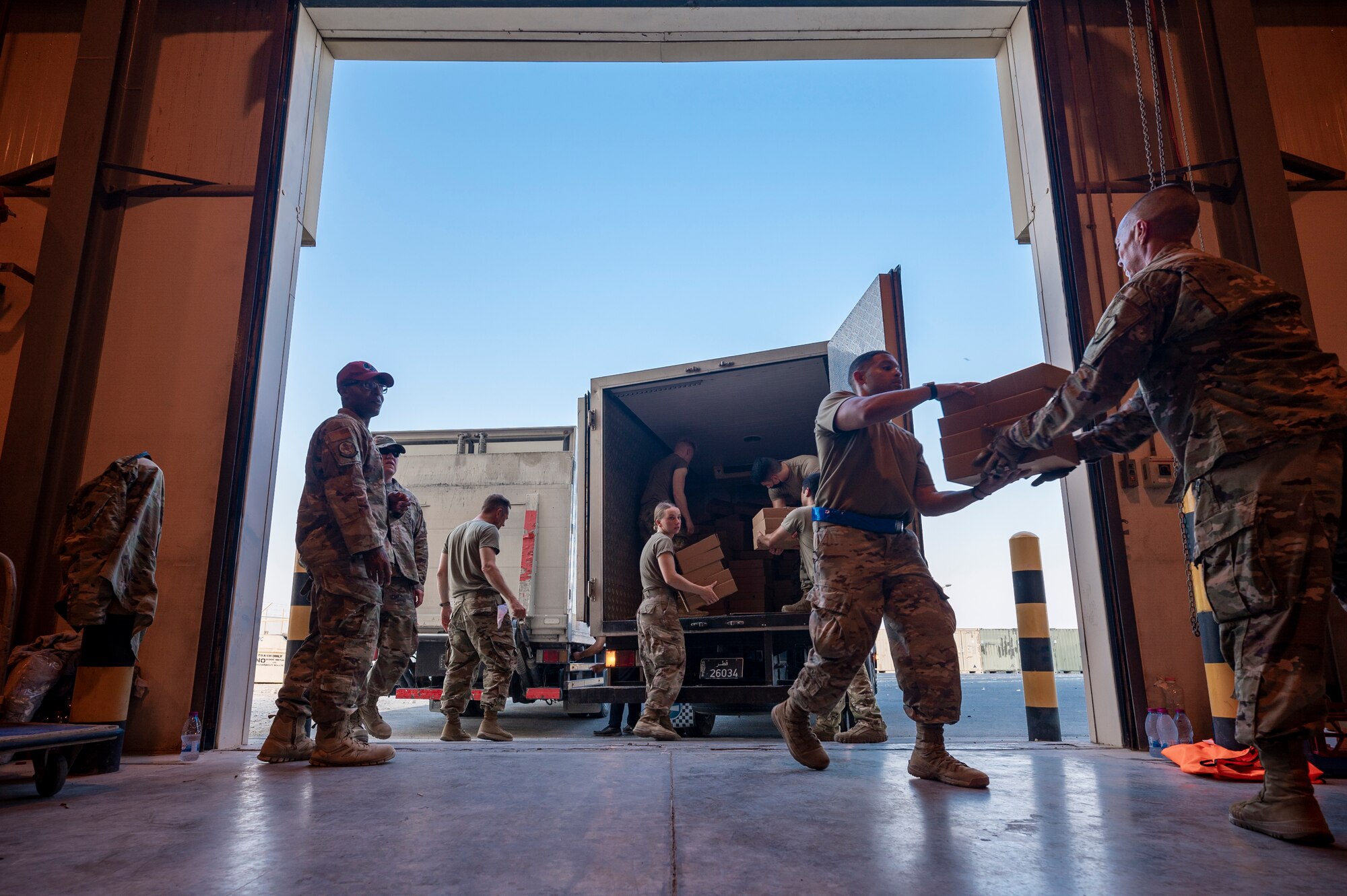 Airmen unload food from a truck for Afghanistan evacuees, Aug. 23, 2021, at Al Udeid Air Base, Qatar.