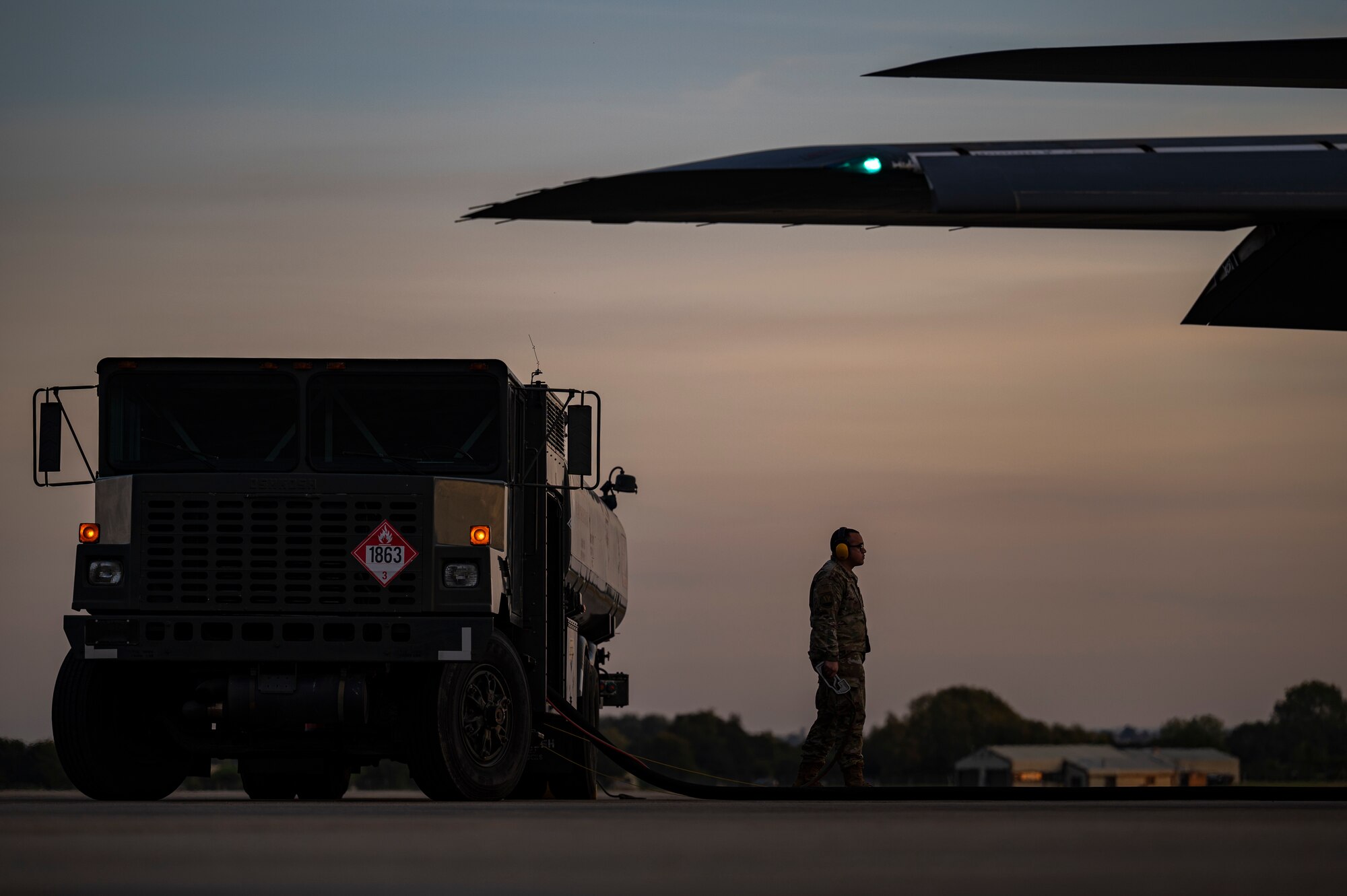 A fuels specialist assigned to the 9th Expeditionary Bomb Squadron, stands by while a B-1B Lancer is being refueled at RAF Fairford, United Kingdom, Oct 11, 2021. Hot pit refueling is the refueling of an aircraft without turning off the engines. These refueling operations give aircrew the ability to conduct multiple mission sets before needing to turn the aircraft over to undergo routine maintenance. (U.S. Air Force photo by Senior Airman Colin Hollowell)