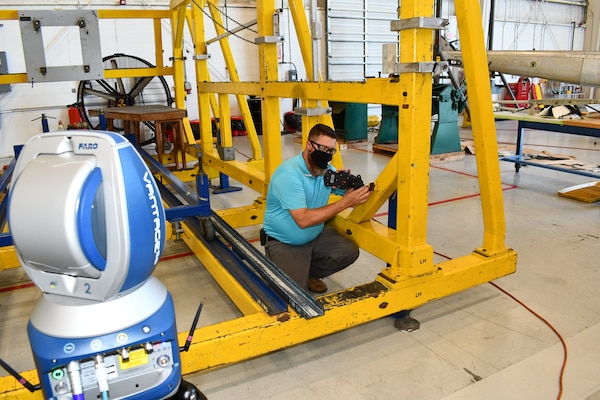 Mechanical engineering technician measures an aircraft alignment fixture using a laser tracking system.