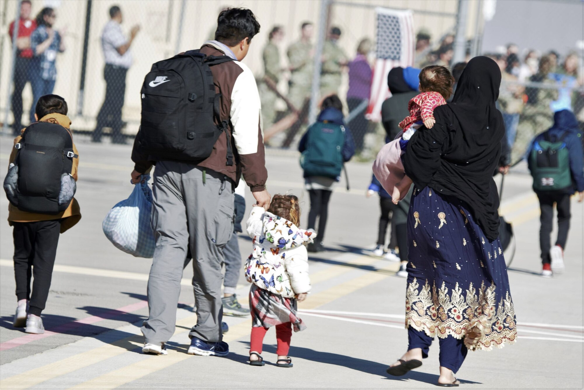 An Afghan family receives a warm welcome as they arrive to Task Force Holloman at Holloman Air Force Base, New Mexico, Oct. 10, 2021. The Department of Defense, through U.S. Northern Command, and in support of the Department of State and Department of Homeland Security, is providing transportation, temporary housing, medical screening, and general support for at least 50,000 Afghan evacuees at suitable facilities, in permanent or temporary structures, as quickly as possible. This initiative provides Afghan evacuees essential support at secure locations outside Afghanistan. (U.S. Navy photo  by Mass Communications Specialist 1st Class Sarah Rolin)