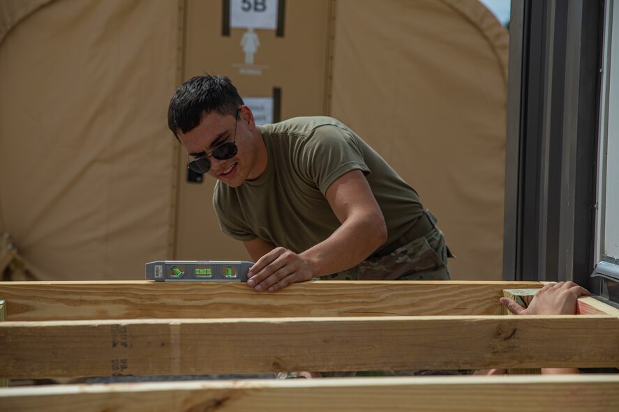 An Airman attached to Task Force Holloman ensures a frame is level as part of improvements to the logistics support area on Holloman Air Force Base, New Mexico, Oct. 8, 2021. The Department of Defense, through U.S. Northern Command, and in support of the Department of Homeland Security, is providing transportation, temporary housing, medical screening, and general support for at least 50,000 Afghan evacuees at suitable facilities, in permanent or temporary structures, as quickly as possible. This initiative provides Afghan personnel essential support at secure locations outside Afghanistan. (U.S. Army photo by Pfc. Anthony Sanchez)