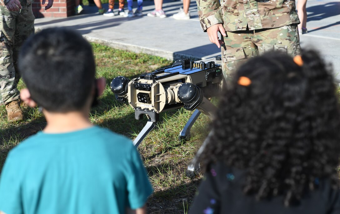 Children look at a robot dog.