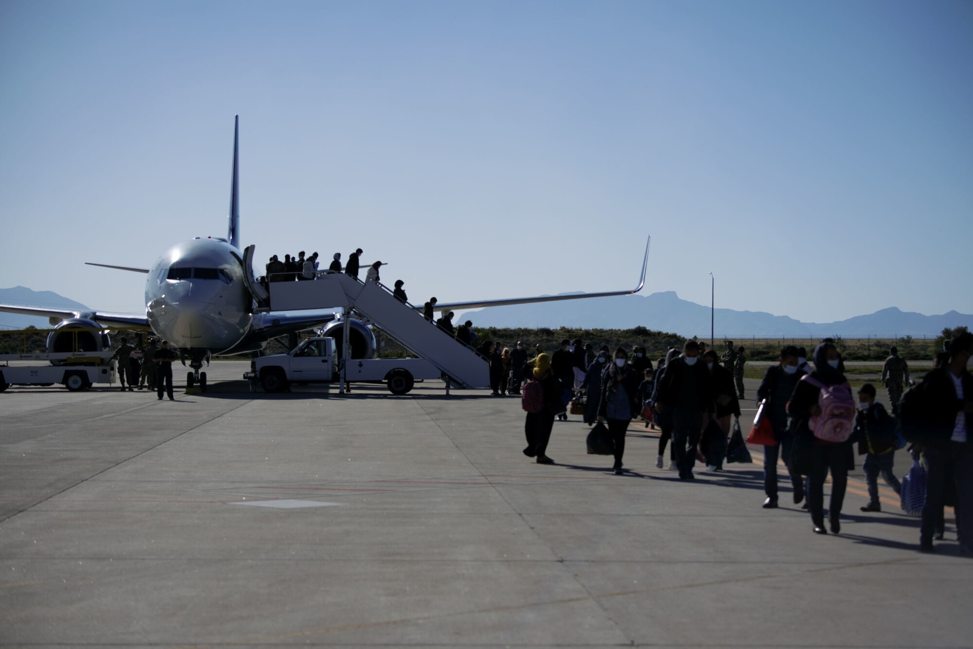 Afghan evacuees arrive to Task Force Holloman at Holloman Air Force Base, New Mexico, Oct. 10, 2021. The Department of Defense, through U.S. Northern Command, and in support of the Department of State and Department of Homeland Security, is providing transportation, temporary housing, medical screening, and general support for at least 50,000 Afghan evacuees at suitable facilities, in permanent or temporary structures, as quickly as possible. This initiative provides Afghan evacuees essential support at secure locations outside Afghanistan. (U.S. Navy photo by Mass Communications Specialist 1st Class Sarah Rolin)