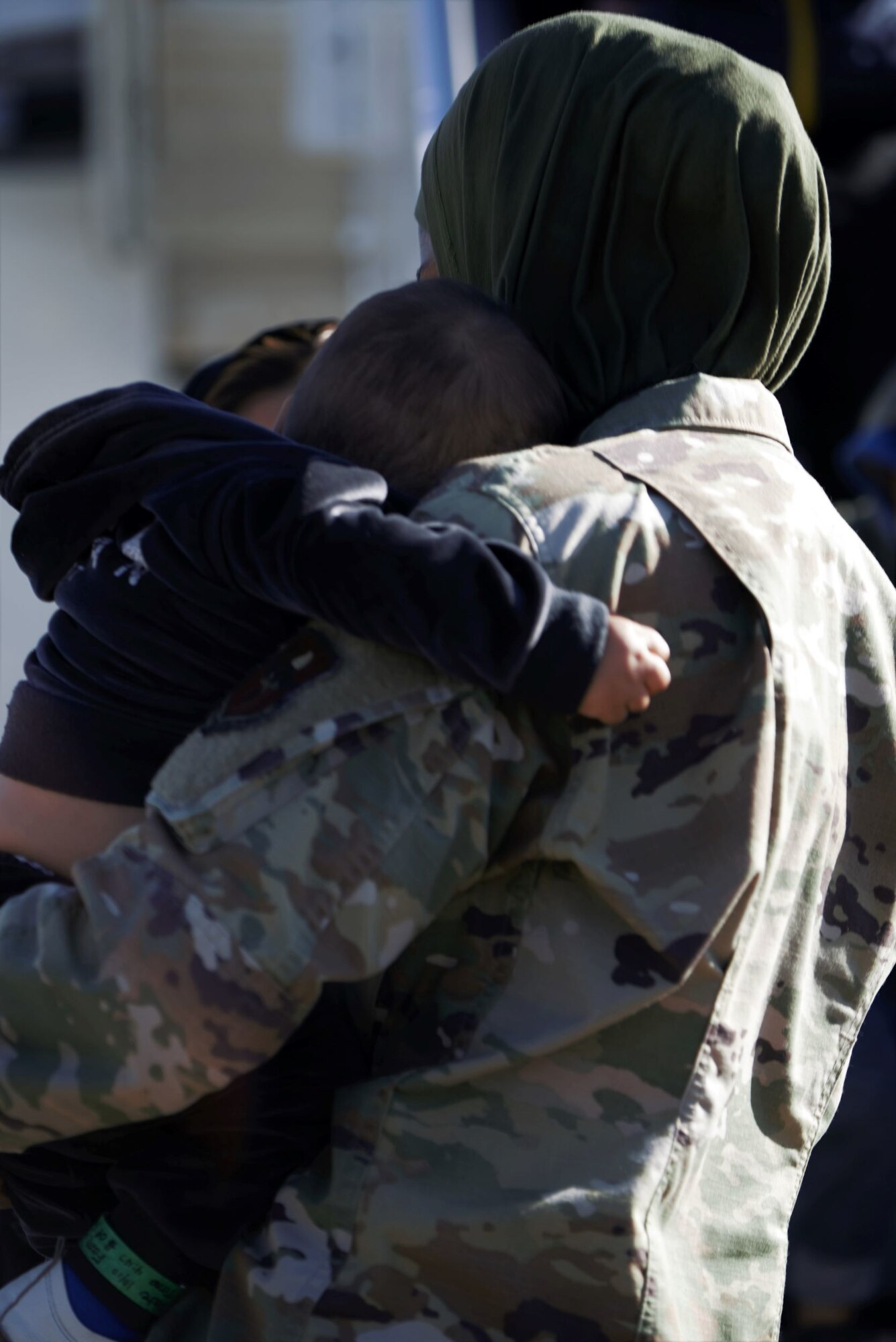 A tired Afghan child rests his head on the shoulder of U.S. Air Force 1st Lt. Saleha Jabeen, a chaplain assigned to Task Force Holloman, after arriving to TF Holloman at Holloman Air Force Base, New Mexico, Oct. 10, 2021. The Department of Defense, through U.S. Northern Command, and in support of the Department of State and Department of Homeland Security, is providing transportation, temporary housing, medical screening, and general support for at least 50,000 Afghan evacuees at suitable facilities, in permanent or temporary structures, as quickly as possible. This initiative provides Afghan evacuees essential support at secure locations outside Afghanistan. (U.S. Navy photo by Mass Communications Specialist 1st Class Sarah Rolin)