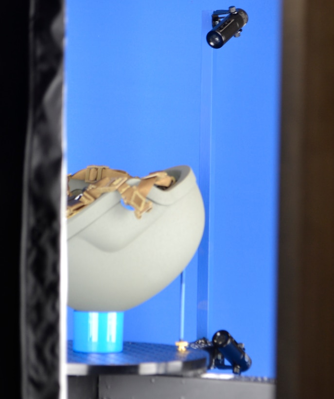 A military helmet sits on a circular metal plate against a blue backdrop.