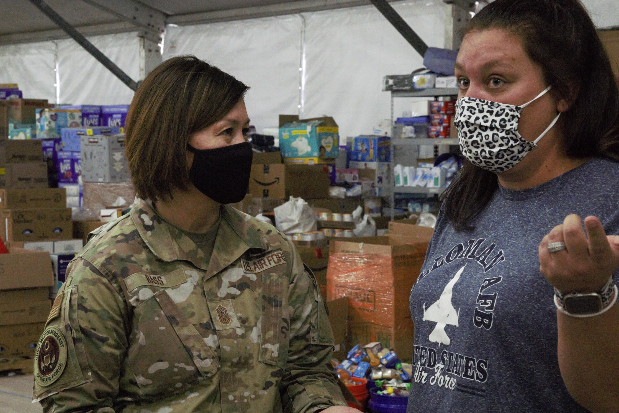Chief Master Sgt. of the Air Force JoAnne S. Bass speaks to Jessica Manco, a member of the Holloman Spouses Organization and lead donations supervisor, about the donations center at Aman Omid Village as part of a visit to Holloman Air Force Base, New Mexico, Oct. 13, 2021. The Department of Defense, through U.S. Northern Command, and in support of the Department of State and Department of Homeland Security, is providing transportation, temporary housing, medical screening, and general support for at least 50,000 Afghan evacuees at suitable facilities, in permanent or temporary structures, as quickly as possible. This initiative provides Afghan evacuees essential support at secure locations outside Afghanistan. (U.S. Navy photo by Mass Communications Specialist 1st Class Sarah Rolin)