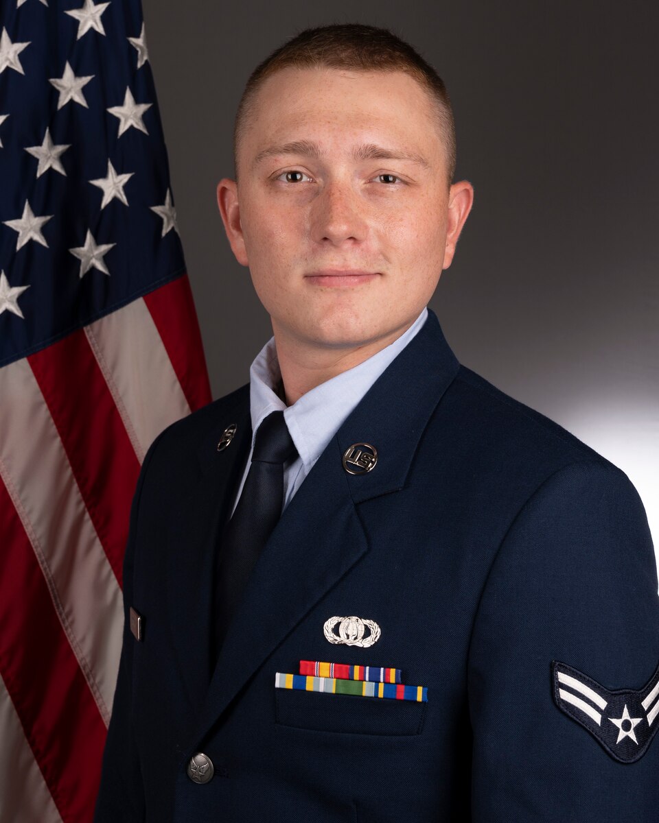 Official photo of A1C Benton Felty, vocalist with Full Spectrum and  Concert Band, two of six ensembles in the Air Force Heritage of America Band, Langley AFB, VA.  A1C Felty is wearing blue service dress in front of an American flag.