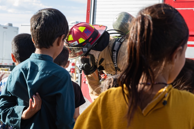 A Task Force-Holloman firefighter speaks with Afghan children at the end of a fire safety class given to young Afghan evacuees on Holloman Air Force Base, New Mexico, Oct. 11, 2021. The Department of Defense, through the U.S. Northern Command, and in support of the Department of State and Department of Homeland Security, is providing transportation, temporary housing, medical screening, and general support for at least 50,000 Afghan evacuees at suitable facilities, in permanent or temporary structures, as quickly as possible. This initiative provides Afghan evacuees essential support at secure locations outside Afghanistan. (U.S. Army photo by Spc. Nicholas Goodman)