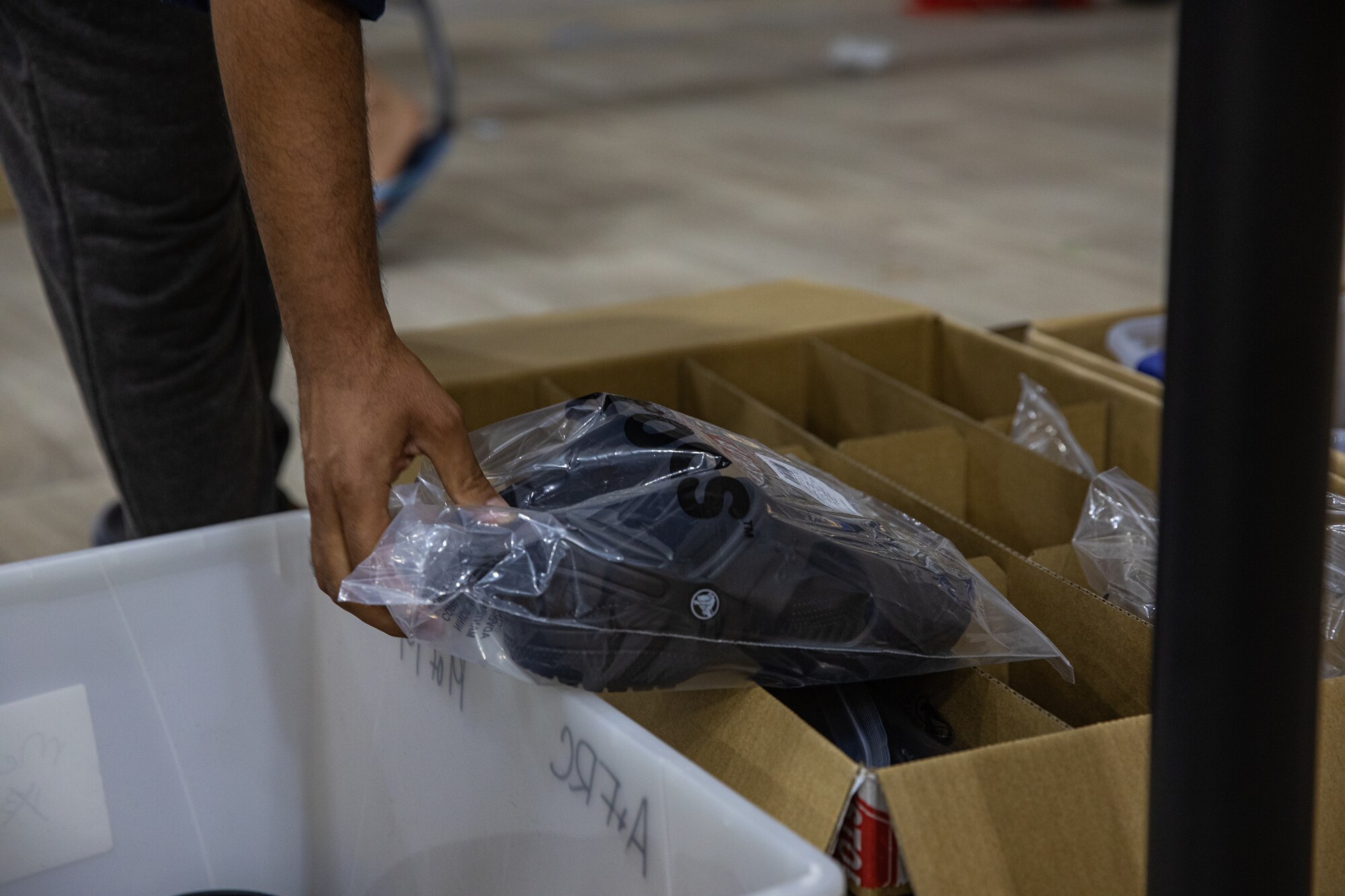 An Afghan evacuee takes a new pair of shoes from the donation center at Task Force-Holloman on Holloman Air Force Base, New Mexico Oct. 9, 2021. The Department of Defense, through U.S. Northern Command, and in support of the Department of Homeland Security, is providing transportation, temporary housing, medical screening, and general support for at least 50,000 Afghan evacuees at suitable facilities, in permanent or temporary structures, as quickly as possible. This initiative provides Afghan personnel essential support at secure locations outside Afghanistan. (U.S. Army photo by Pfc. Anthony Sanchez)