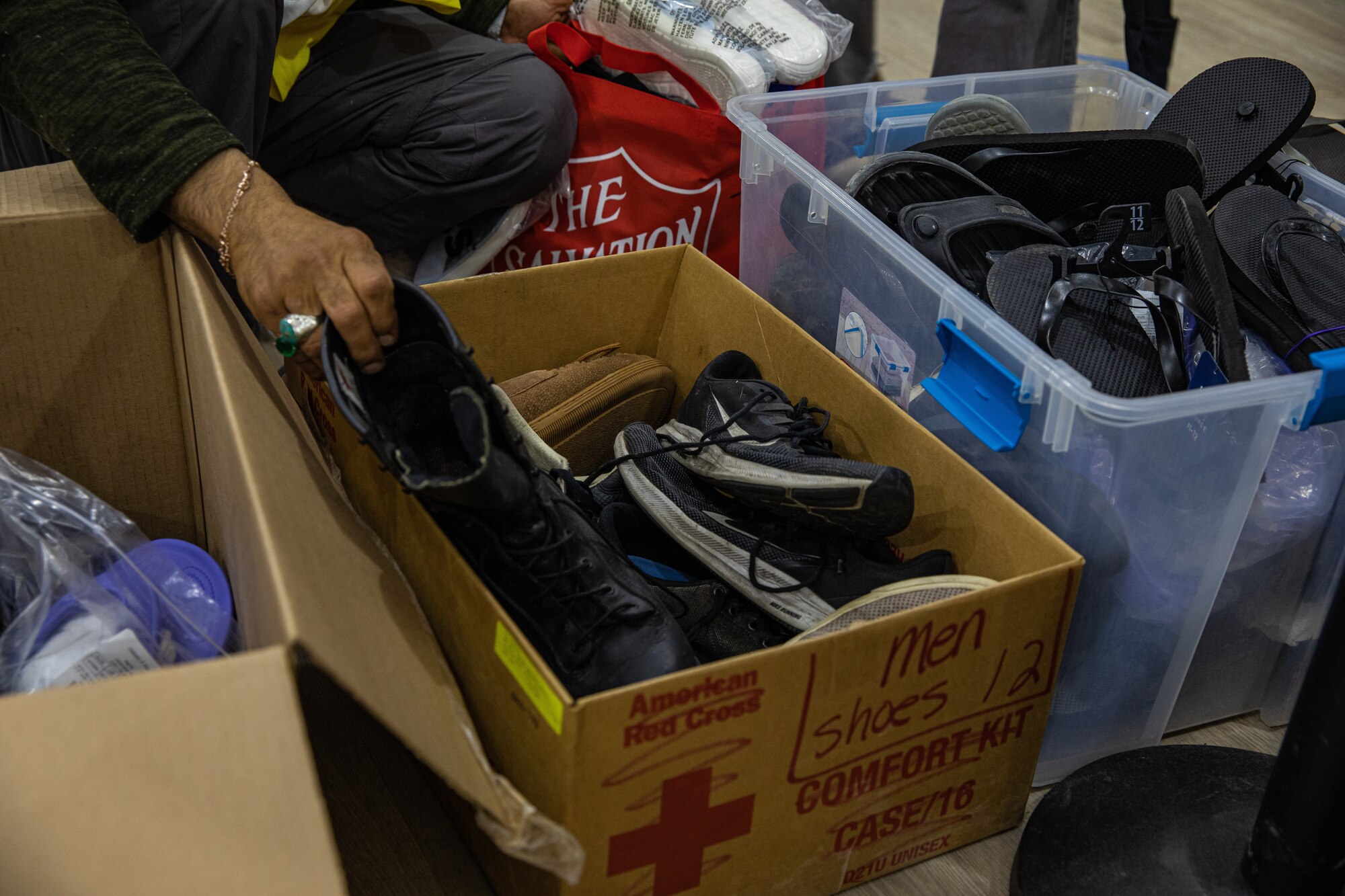 An Afghan evacuee looks through donated shoes from the donation center at Task Force-Holloman on Holloman Air Force Base, New Mexico Oct. 9, 2021.The Department of Defense, through U.S. Northern Command, and in support of the Department of Homeland Security, is providing transportation, temporary housing, medical screening, and general support for at least 50,000 Afghan evacuees at suitable facilities, in permanent or temporary structures, as quickly as possible. This initiative provides Afghan personnel essential support at secure locations outside Afghanistan. (U.S. Army photo by Pfc. Anthony Sanchez)