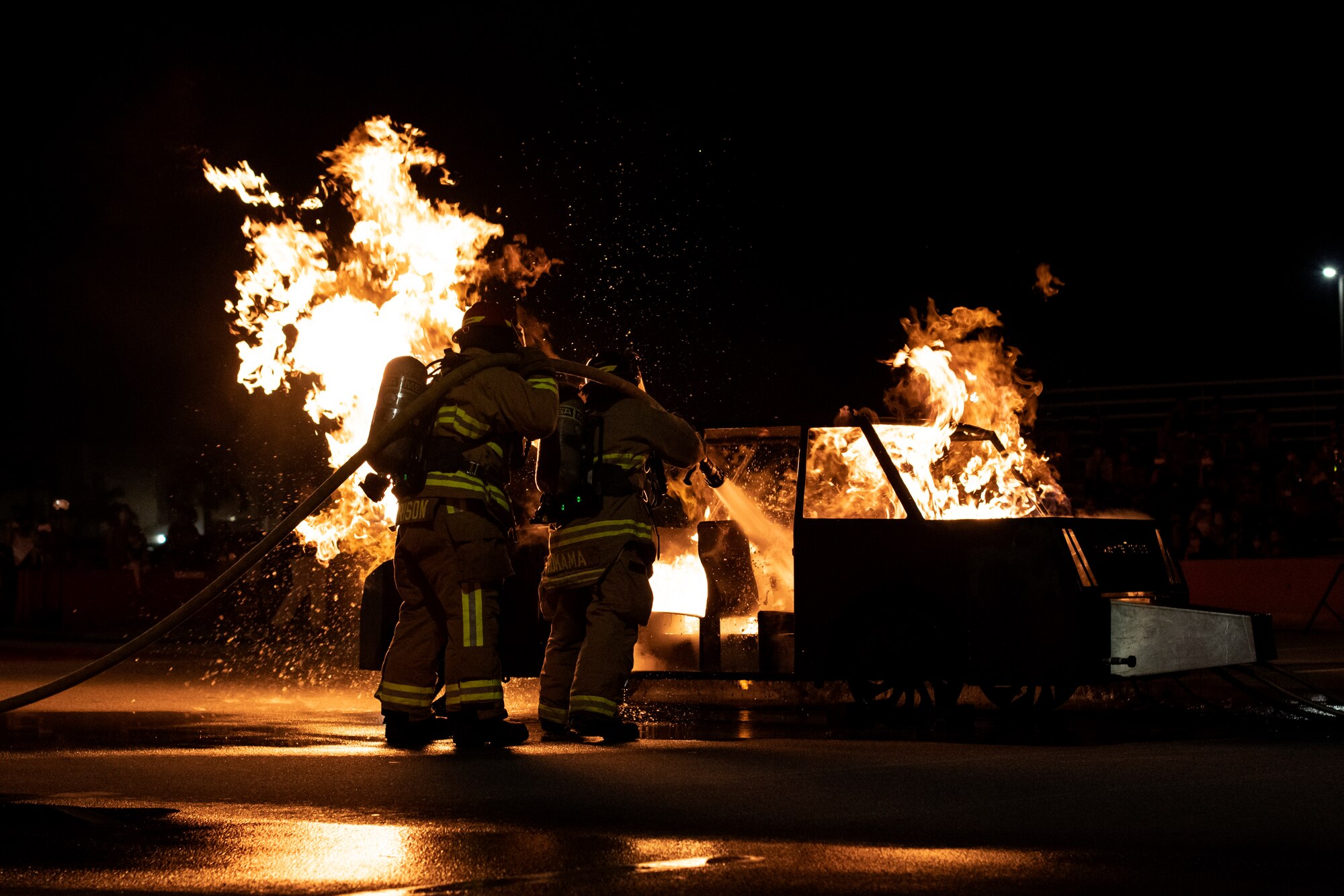 U.S. Air Force Staff Sgt. Garrett Morrison, 18th Civil Engineering Squadron firefighter, left, and Reiki Hokama, 18th CES firefighter, fight a simulated car fire during a Fire Prevention Week demonstration at Kadena Air Base, Japan, Oct. 7, 2021. Since 1922, FPW has been observed annually during the week of Oct. 9 in remembrance of the Great Chicago Fire of 1871. (U.S. Air Force photo by Senior Airman Jessi Monte)